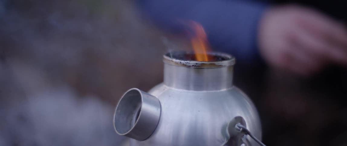 A camping stove burns and plumes smoke