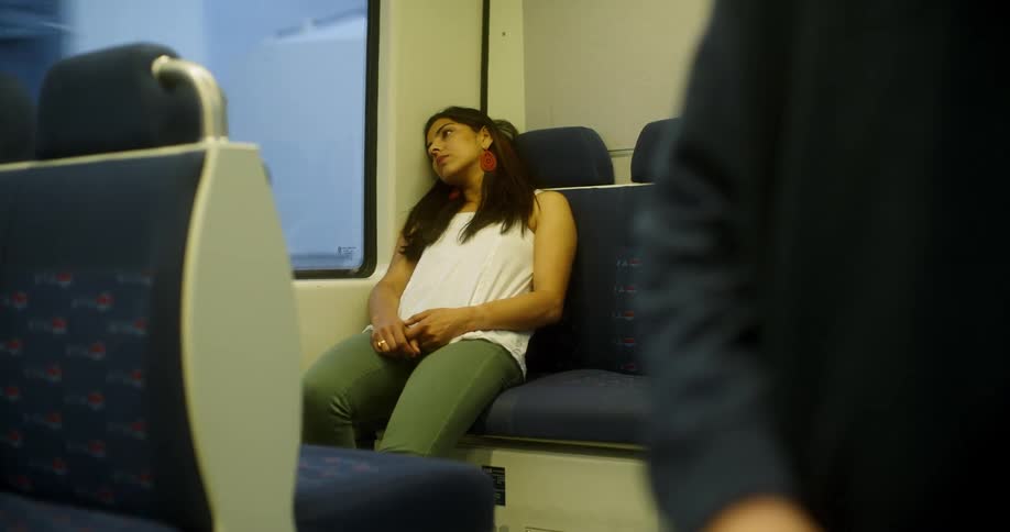 A woman sits slouched down in a train seat by a window