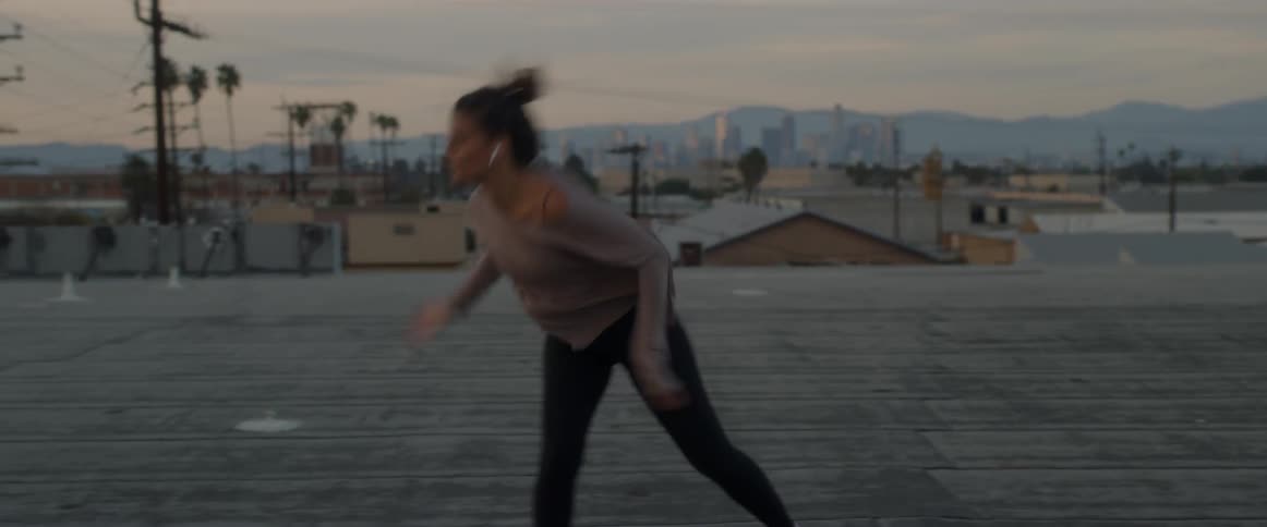 A woman does a complicated dance routine on a rooftop
