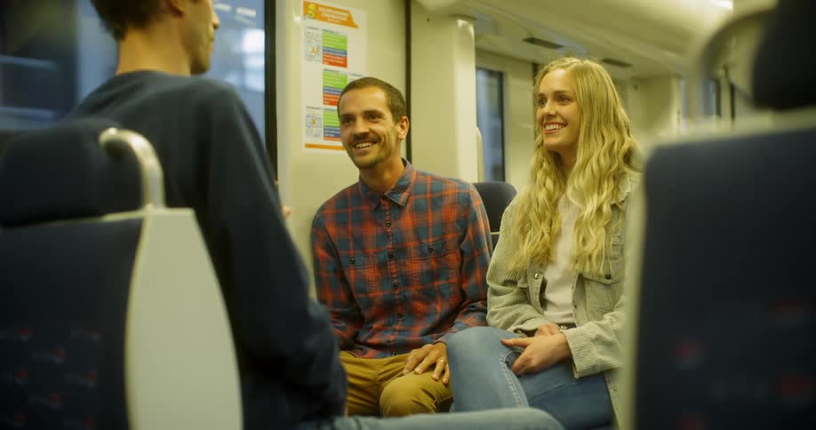 Smiling woman talking and laughing with two men in a train