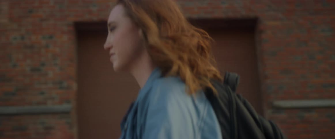A woman walking next to a red bricked building