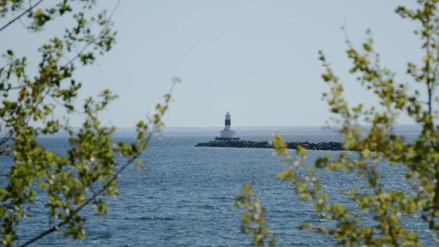 A lighthouse stands on a small peninsula that reaches out into an ocean