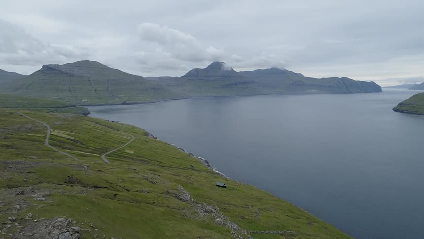 A landscape featuring mountains, hills, and a lake is shown