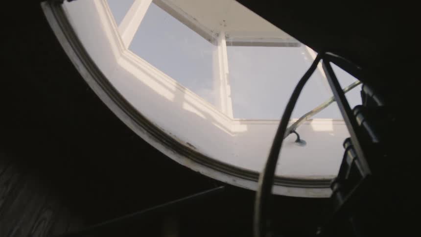 Winding stairs lead up to windows showing a mostly clear sky