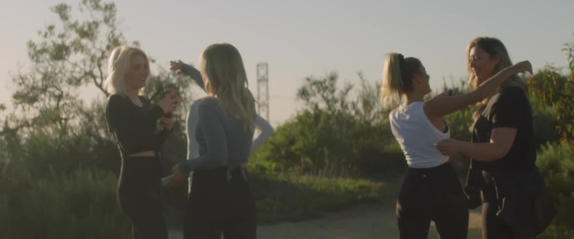 Five female friends embracing each other in hugs smiling as they meet up outside