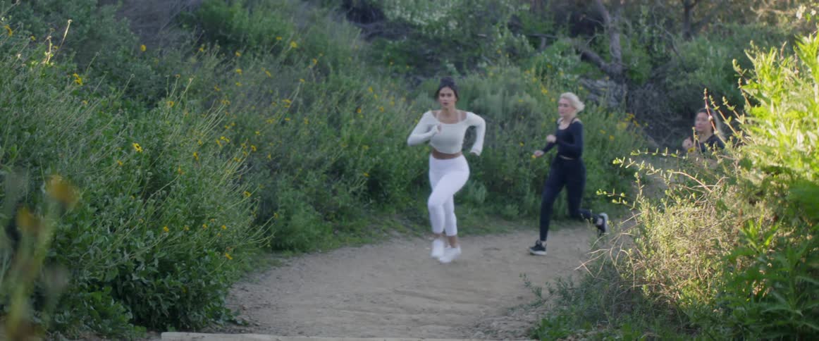Women running on a dirt road on a bright day