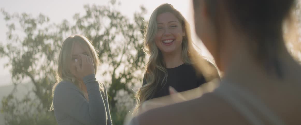 A woman taking a picture of two women on a sunny day