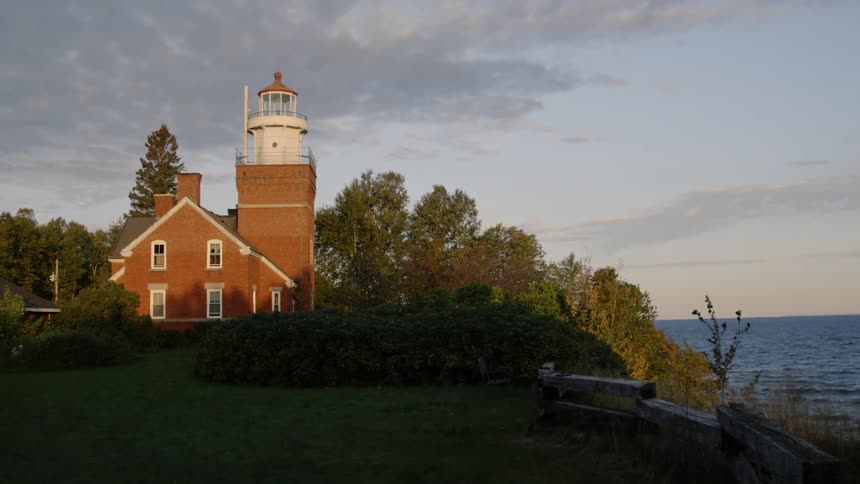 Trees blowing in the wind next to a small lighthouse