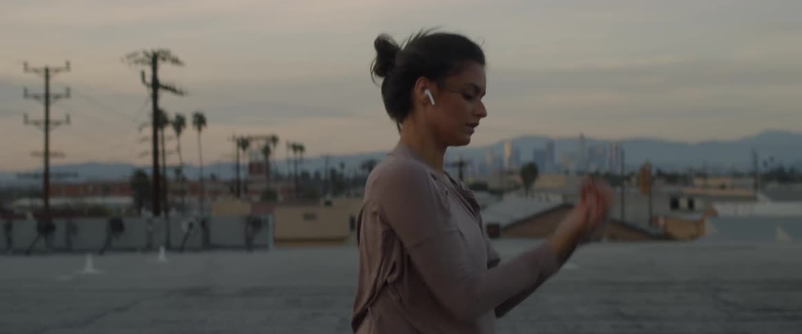 Woman wearing earphones dancing on a city rooftop