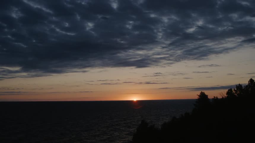 The sun setting at the end of the horizon at the ocean