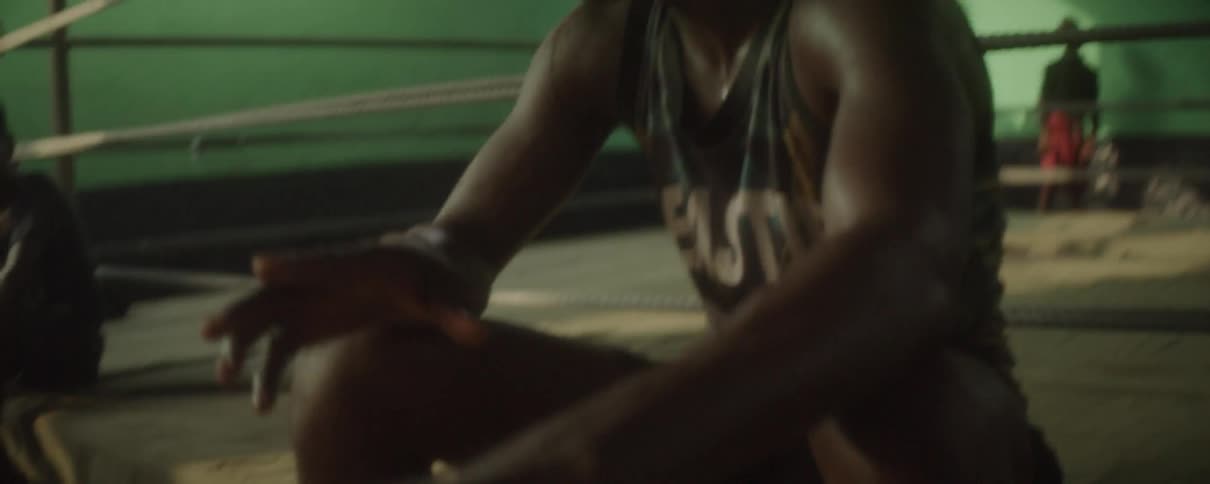 A man is sitting just outside the boxing ring