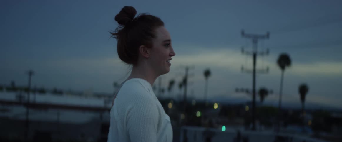 Smiling woman walks in the city at sunset