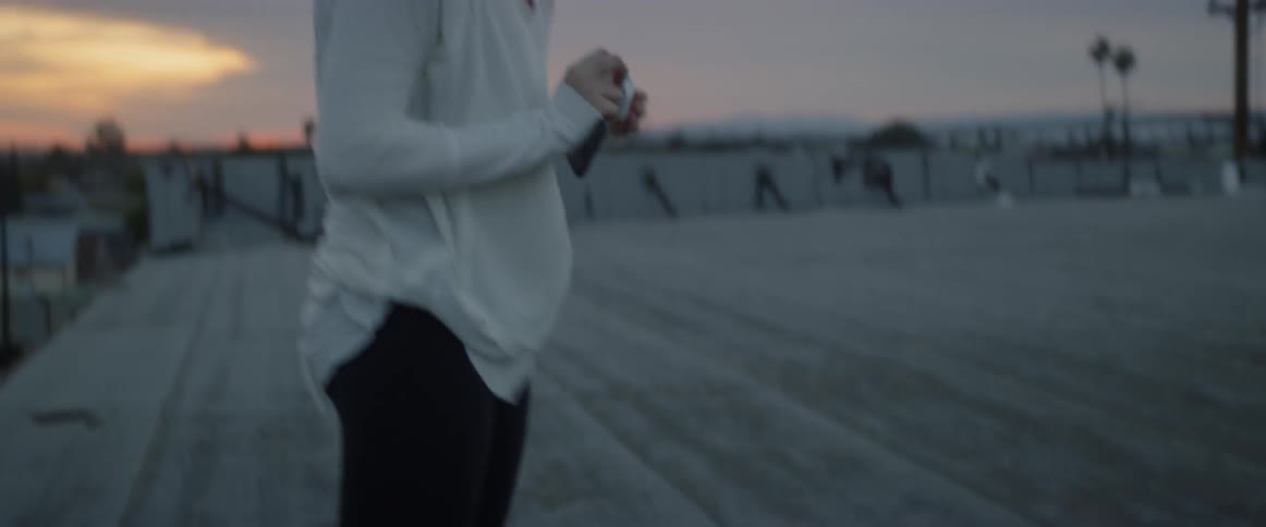 A woman puts ear buds in outside