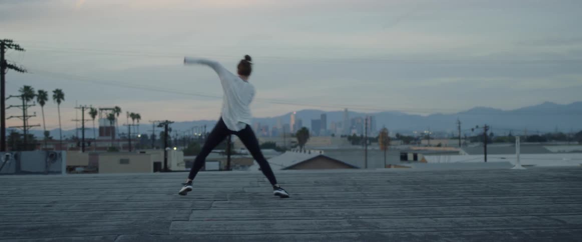 Woman dancing on rooftop on a cloudy day
