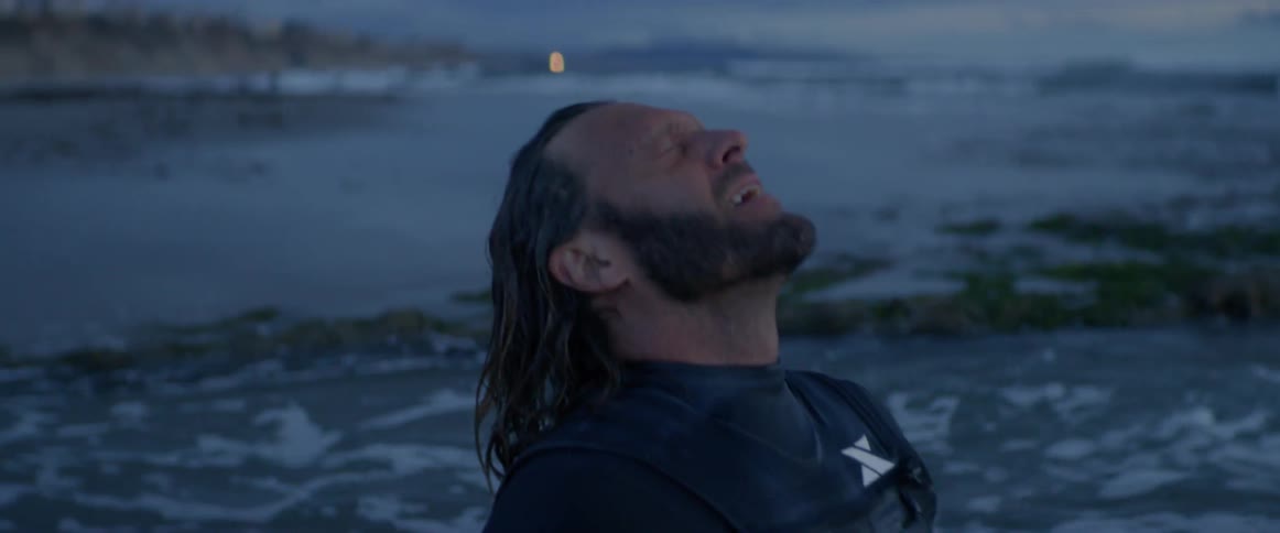 Man splashes water on his face and hair at sunset