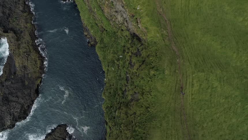 Birds fly around a tall cliff in the middle of a vast body of water