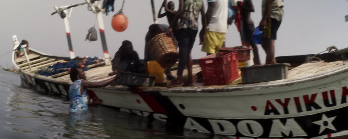 A group of men on a boat dump baskets of water into another basket