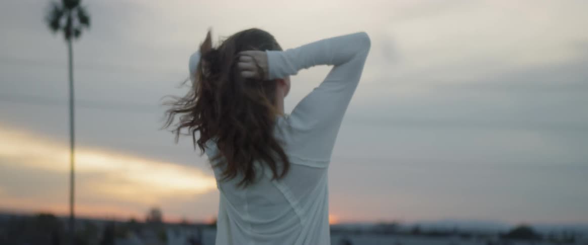 Woman tying her hair outdoors during sunrise