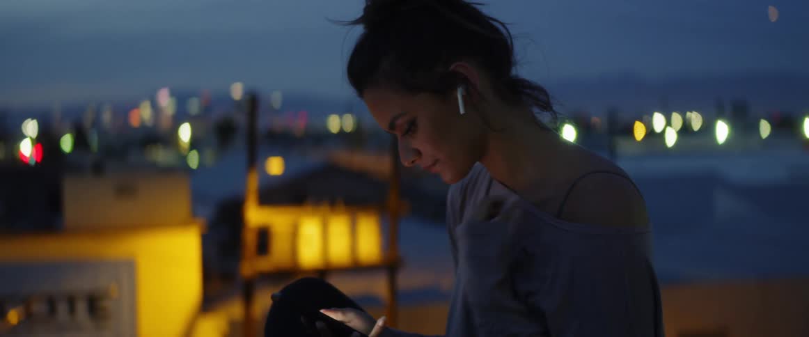 A woman uses her phone outside at night
