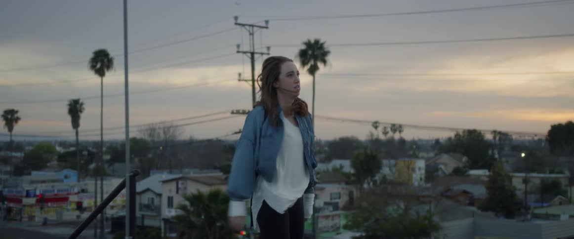 Woman walks up a staircase outside and stands on a rooftop