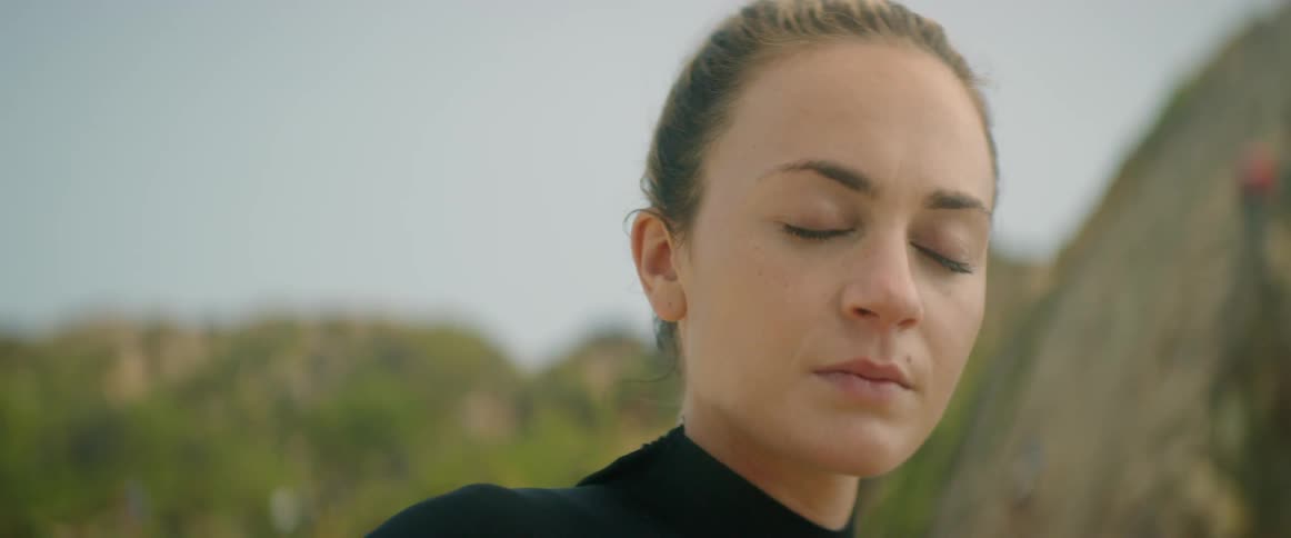 A woman with a wet suit closing her eyes and concentrating