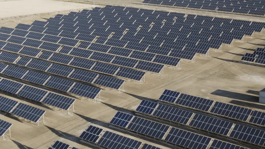 Solar panels lie along a field in the desert