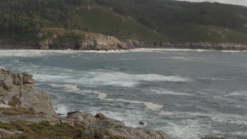 Ocean waves crash on rocks on a cloudy day
