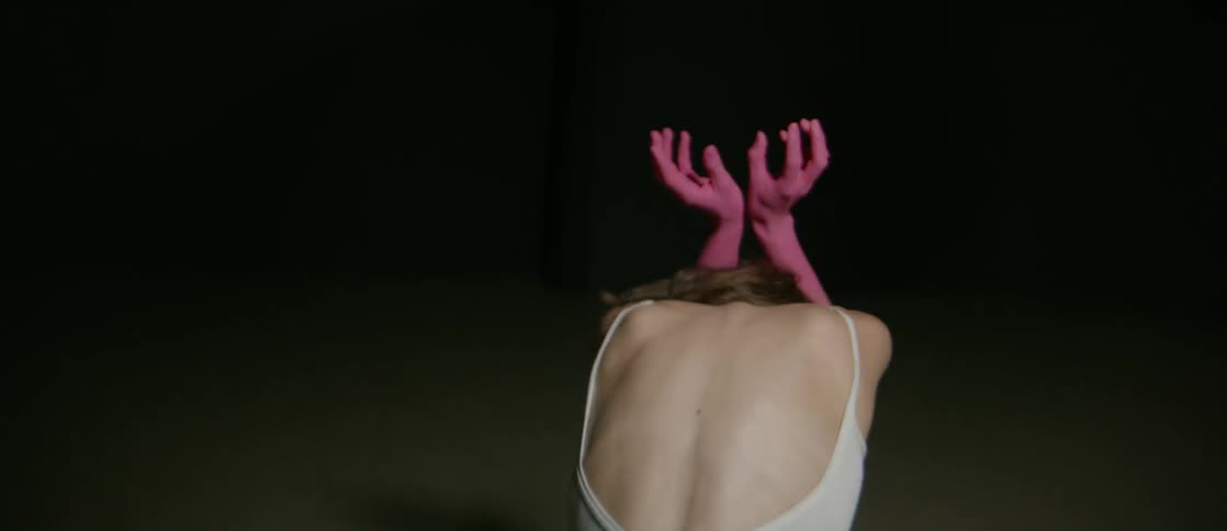 Woman with pink paint on her hands waves her arms and crouches