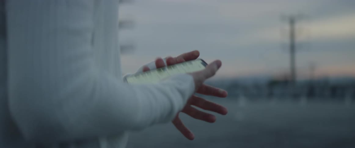 Person standing outside at sunset looks at their phone