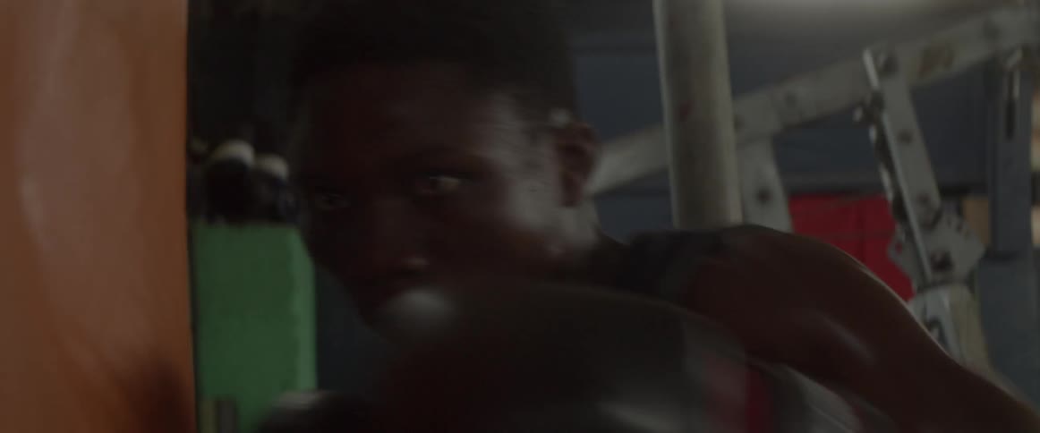 Man wearing boxing gloves moves forward and punches a punching bag