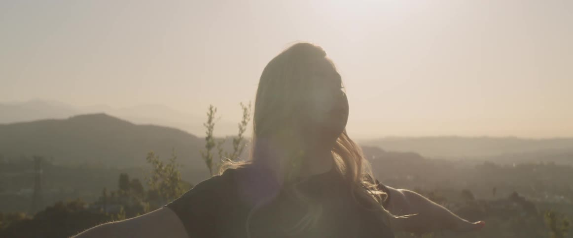 A woman does yoga under the sun on a cloudless day