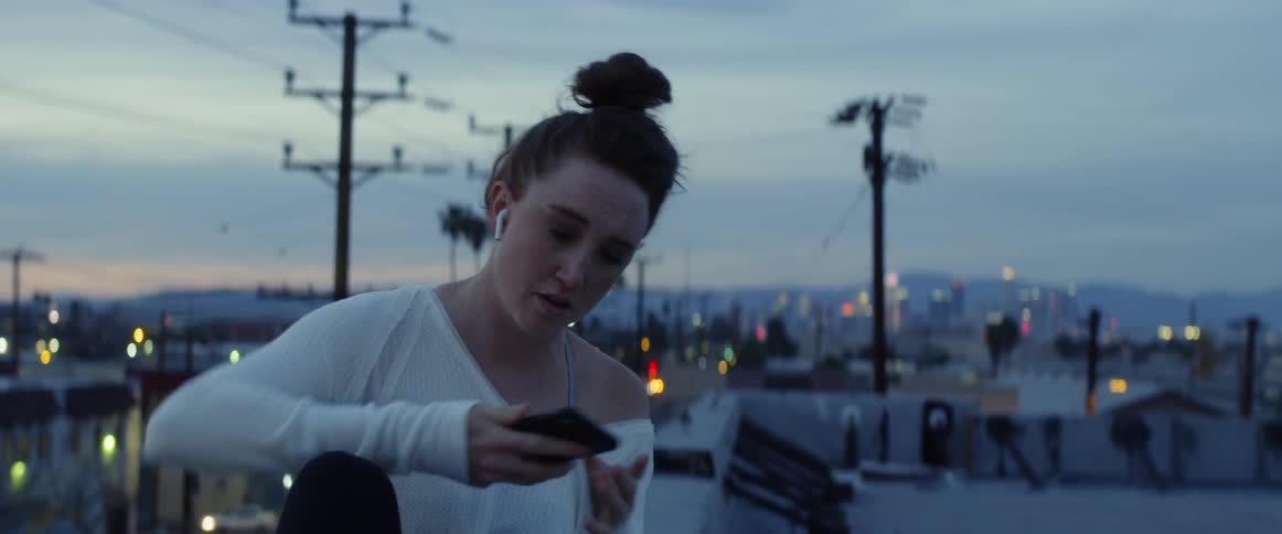 A woman sitting down on the roof ledge in a city