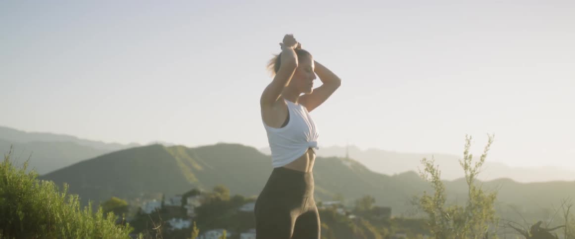Woman outside puts hair in ponytail