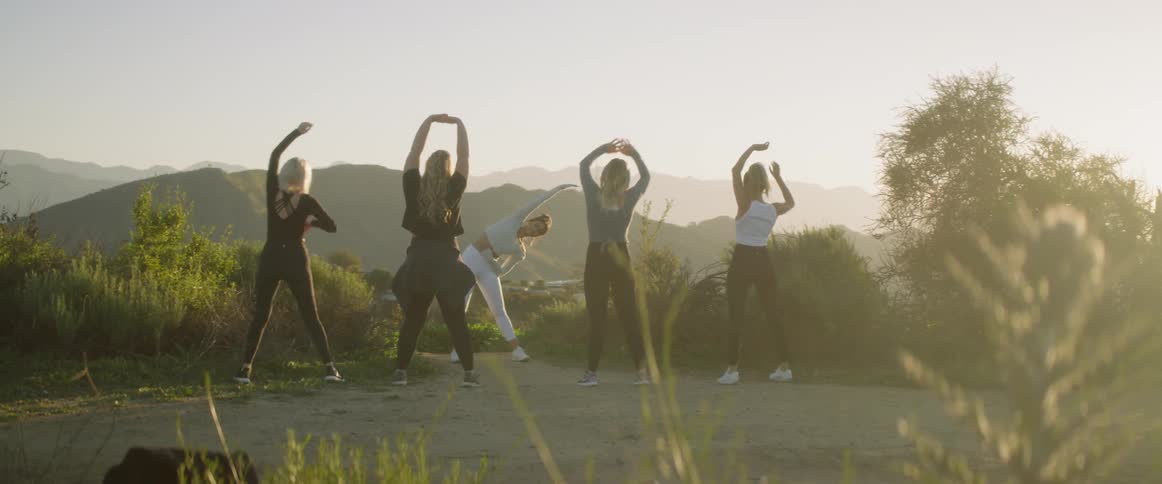A group of women that are doing stretches on a trail