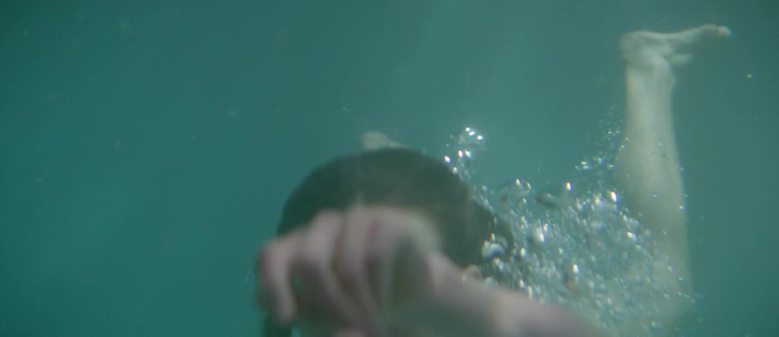 Woman holds hands out in front of body, while diving under water