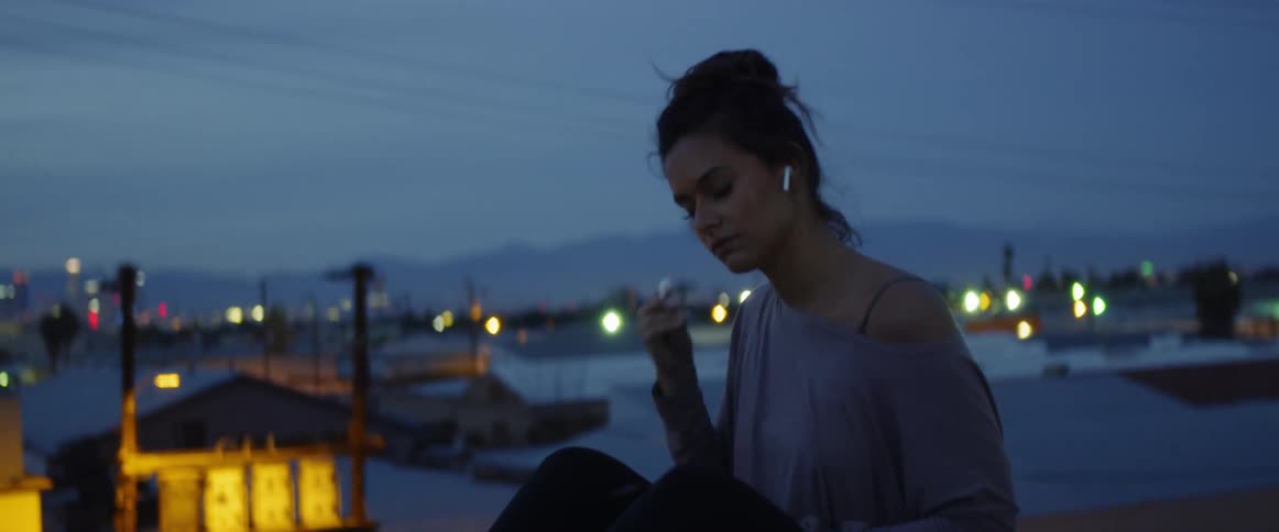 A woman puts on earbuds and starts looking at her phone