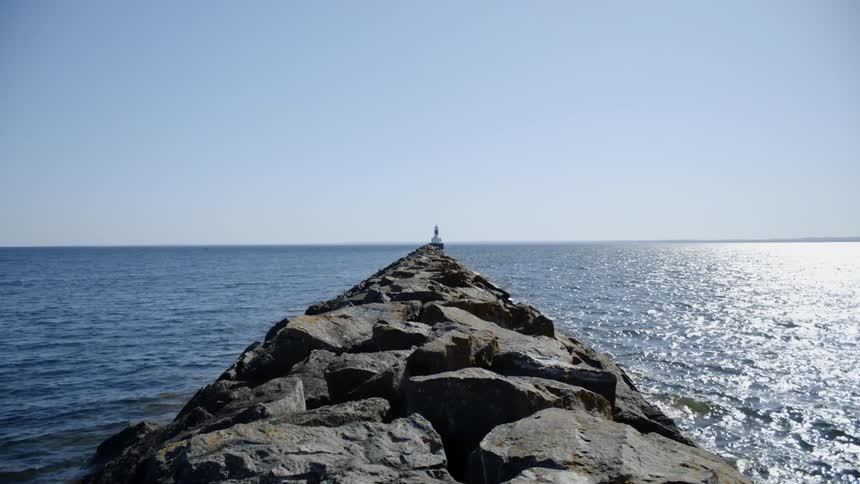 Calm sea moving around a long rocky pier