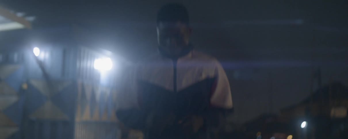 A man wearing a windbreaker jogs down a street at night