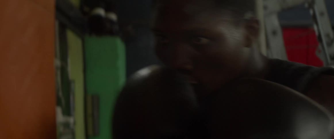 Man wearing black gloves is punching an orange bag