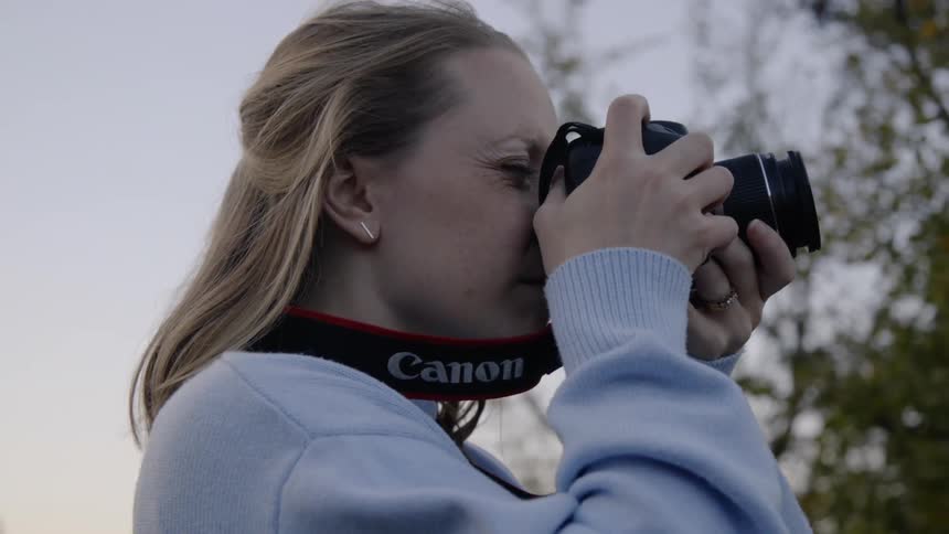 A woman looking through a camera taking a photo