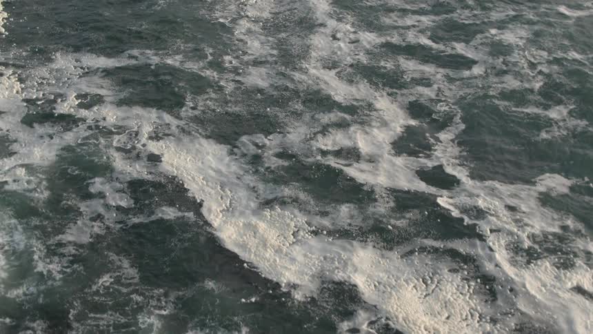 The ocean roils choppily below us as we move over it in the air
