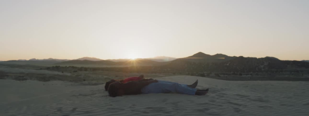 Two people lay on the sand in the desert
