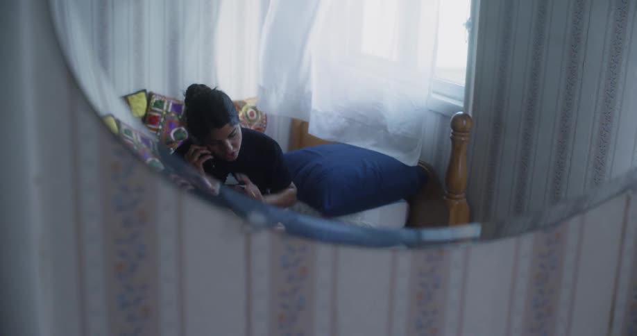 Wind blowing a curtain beside a woman speaking on the phone