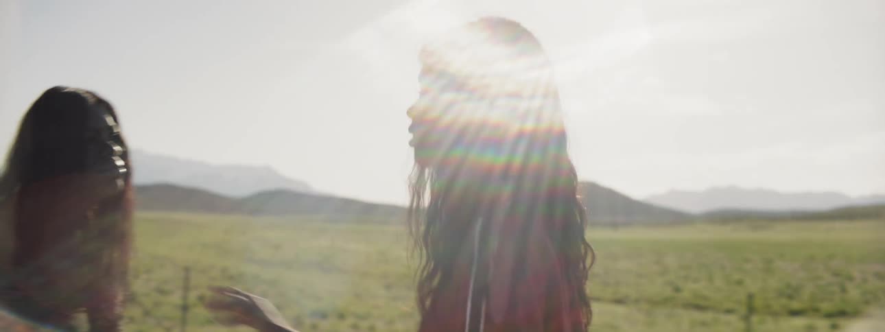 Two women talking to each other on the side of a field