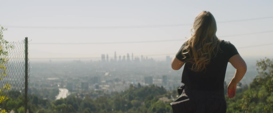 Running woman stops and look at a city skyline