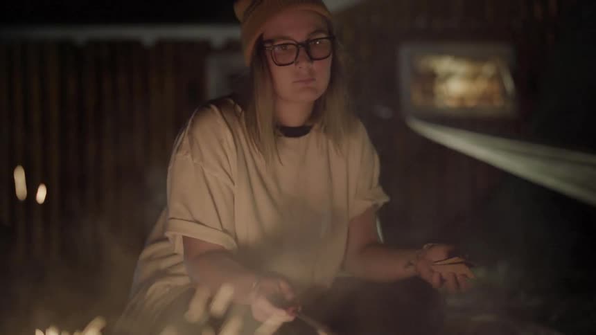 Woman roasts marshmallows in a campfire at night