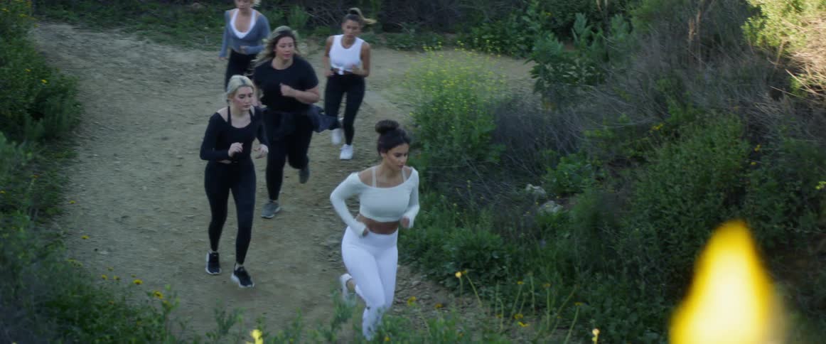 A group of women jog along a dirt path in the countryside