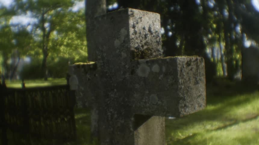 The sun shines brightly on a cross shaped grave marker in a cemetery