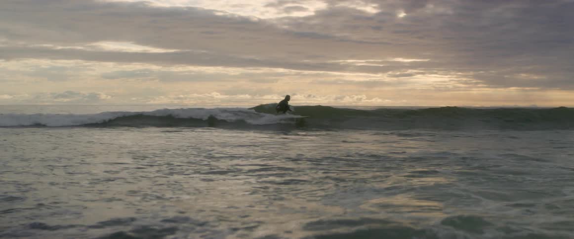A surfer rides a wave towards the shore