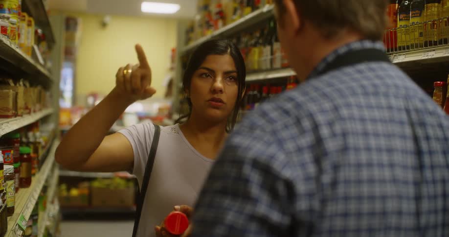 A woman asks a man for help in a grocery store